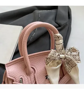 Detail der rosa Handtasche aus Leder mit Seidenschal am Griff und silbernem Schloss