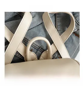 Top detail of cream white leather backpack showing reinforced handle and smooth texture