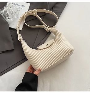Close-up of beige pleated faux leather handbag with flap closure and adjustable strap