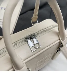 Détails de la double fermeture éclair en métal argenté sur un sac à bandoulière crème