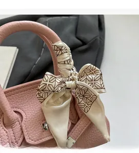 Detailansicht eines rosa Lederhandtaschengriffs umwickelt mit einem bedruckten Seidentuch