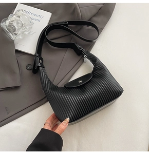 Detail of black pleated texture on crescent bag with silver zipper and leather strap