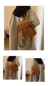 Detail of vintage brown suede backpack featuring a buckle flap and drawstring closure