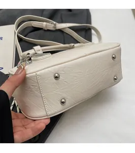 Détail du sac bowling blanc avec rivets métalliques de protection et cuir froissé