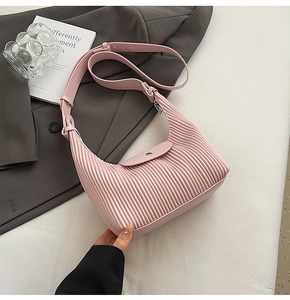 Detail of pink pleated crescent bag with adjustable leather strap on a white surface