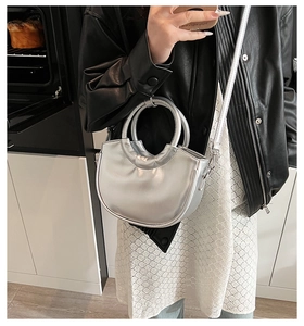 Détail d'un sac à main croissant argenté avec poignées cylindriques sur un mannequin