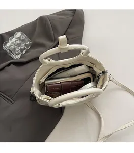 Vue intérieure du sac en cuir crème montrant sa grande capacité et sa poche zippée
