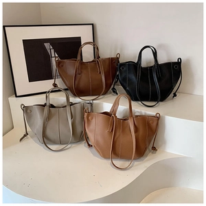Sacs cabas motif litchi en café, noir, gris et beige exposés sur un escalier