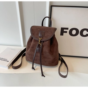 Detail of vintage brown suede backpack with faux leather trim and drawstring closure