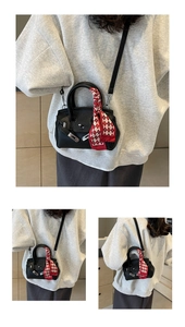 Detail der schwarzen Lederhandtasche mit rotem Seidentuch auf grauem Sweatshirt