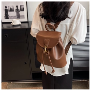 Detail of vintage brown leather backpack with gold metal hook and drawstring closure