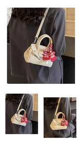 Details einer beige Lederhandtasche mit Seidenschal-Dekor und silbernem Metallschnallen-Verschluss
