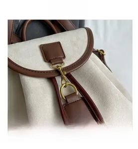Détail du crochet en métal doré vintage sur sac à dos beige givré avec bordure marron