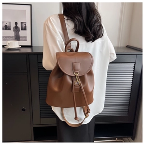Close-up of brown leather backpack with drawstring closure and golden metal hook details