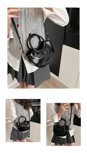 Détail d'un sac à main croissant noir brillant avec poignée ronde et bandoulière réglable