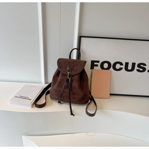 Detail of dark brown faux suede backpack with drawstring closure and metal buckle strap