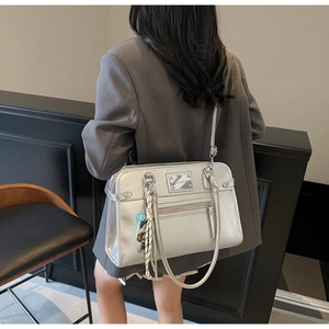 Silver metallic tote bag with fringe charm styled on model with a grey blazer outfit