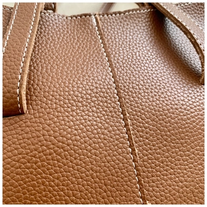 Gros plan sur la texture du cuir grainé marron avec des coutures contrastées blanches