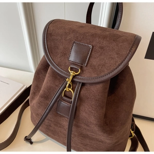 Detail of vintage brown suede backpack with gold hook closure and dark leather trim