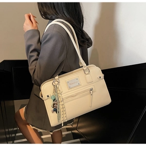 Close-up of cream faux leather shoulder bag featuring silver metal plate and zipper detail