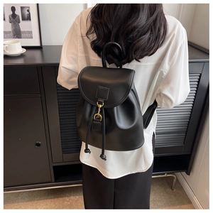Detailed view of black leather backpack featuring gold ring clasp and drawstring closure