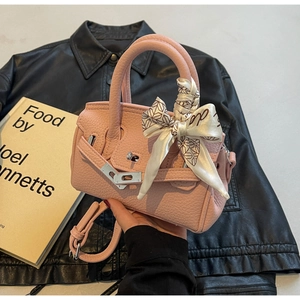 Detail einer rosa Handtasche aus Kieselleder mit Seidenschal und Metalldrehverschluss