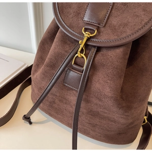 Close-up of brown suede travel backpack with dark leather drawstring and gold metal hardware