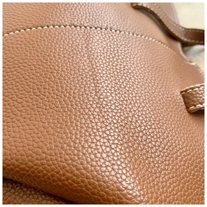 Gros plan sur le cuir grainé marron et les surpiqûres blanches contrastées du sac