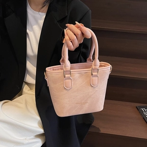 Pink leather bucket tote bag with top handle and golden metal hardware on model