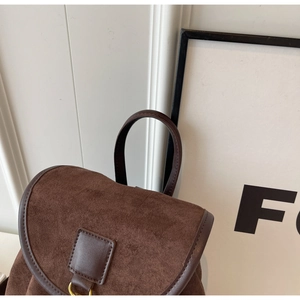 Detailed close-up of dark brown suede texture and metal ring buckle on minimalist backpack