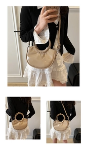 Détail d'un sac demi-lune beige brillant avec poignée ronde et bandoulière réglable