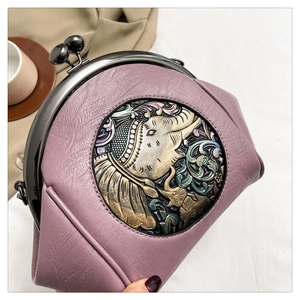 Close-up of retro shell bag featuring embossed metal elephant motif and pink leather texture