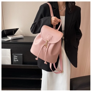 Pink PU leather backpack showing drawstrings and gold buckle detail on a model