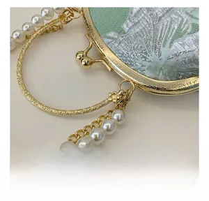 Detail of green floral jacquard fabric with vintage double bead lock and gold handle