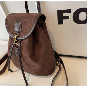 Detail of dark brown suede backpack showing drawstring closure and retro gold hardware
