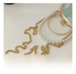 Detail of golden metal chain and white pearl handle on green jacquard handbag
