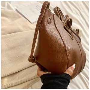 Gros plan d'un sac seau en cuir grainé marron avec des surpiqûres blanches contrastées