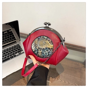 Detailed macro of red faux leather shell bag featuring ethnic elephant relief and metal clasp