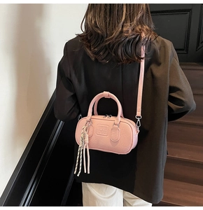 Sac bowling rose clair avec gaufrage UOR UOR et pendentif tressé porté par un modèle