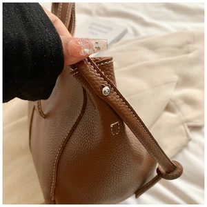 Détail du sac cabas en cuir marron grainé montrant les surpiqûres et les rivets