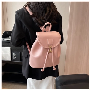 Rear view of a model wearing a large capacity light pink leather backpack with gold buckle
