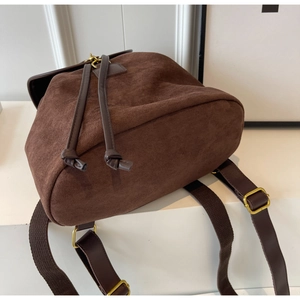 Detail of dark brown faux suede backpack featuring drawstring closure and bronze buckle