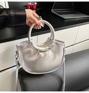 Détails d'un sac demi-lune argenté avec poignée métallique circulaire et bandoulière