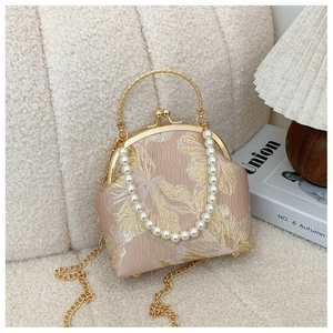 Close-up of pink floral jacquard embroidery on a retro clasp bag with pearl handle chain