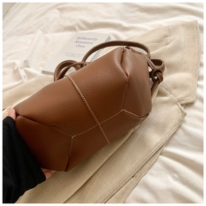 Détail du sac à main en cuir grainé marron avec surpiqûres blanches et design géométrique