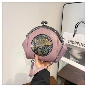 Close-up of pink shell bag featuring an embossed elephant medallion and metal clasp