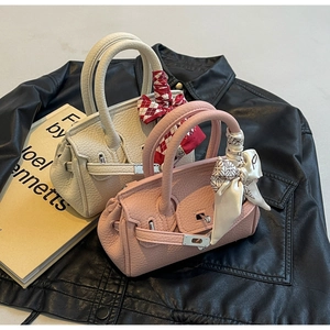 Nahaufnahme von Mini-Handtaschen aus Leder mit Seidenschal und Metalldrehverschluss