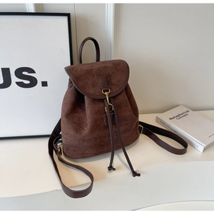 Detail of dark brown suede backpack featuring a drawstring closure and vintage metal hook