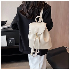Detail view of cream leather backpack with drawstring closure and metal buckle on a model