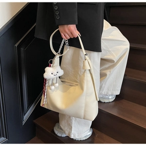 Detail of lychee pattern leather tote bag with cloud charm and ribbon decoration